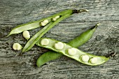 Broad beans in the pod on a wooden surface