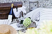 Romantic picnic with cushions, sparkling wine and picnic basket on gravel floor