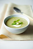 pea soup in the bowl with fresh pea leaves and spoon