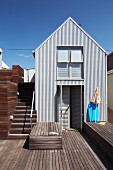 Holzterrasse mit Liegepodest vor südafrikanischem Strandhaus mit Blechfassade im Industriestil