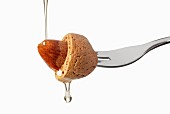An almond on a fork with oil droplets