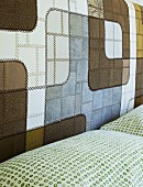 Fine leather patchwork in contrasting natural colours at head of double bed; pillows with pattern of small, green circles