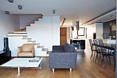 Open-plan living area in architect-designed house with minimalist furnishings and staircase without handrail