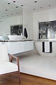 Modernes Bad Ensuite mit großem Wandspiegel, Waschtisch und Badewanne auf weißem Podest
