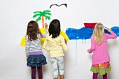 Three children painting the sea & an island on a wall
