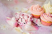Cupcakes with buttercream, sugared almonds and pink decorative birds for a wedding