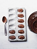 A madeleine tin with chocolate cake mixture