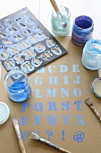 Buchstaben-Schablone, Pinsel und blaue Farbe