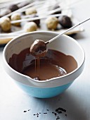 Cake pops being dipped in melted chocolate