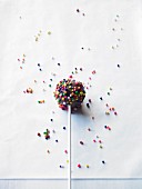 A cake pop decorated with colourful sugar balls