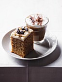 A cube of cappuccino cake and a glass of cappuccino