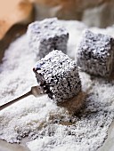 Lamingtons being coated in grated coconut