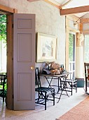 Stühle und Tisch an Wand der Veranda eines Landhauses
