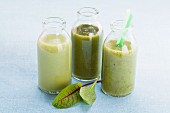 Three green smoothies in glass bottles