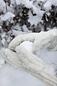 Hands in white fur gloves holding snowball