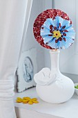 Colourful paper flowers in white china vase