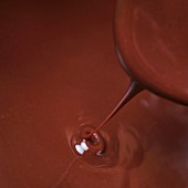 Chocolate sauce dripping from a spoon into a hot pot