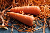 Two carrots next to a mound of carrot peelings