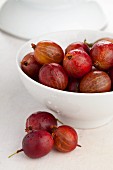 Red gooseberries in a white bowl and in front