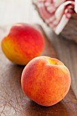 Two whole peaches on a wooden board