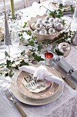 Festlich gedeckter Weihnachtstisch mit Deko in Silber, lindgrünen Kerzen und Efeuranken