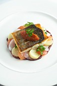 Fried sea bass fillet on a bed of vegetables
