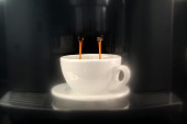 Coffee dripping out of an espresso machine into the cup