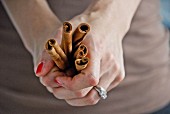 A woman's hands holding cinnamon sticks