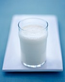 Ein Glas Milch auf weisser Servierplatte