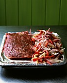 A joint of beef and vegetables in a roasting tin with aluminium foil