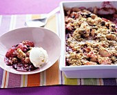 Rhubarb crumble in a baking tin and on a plate with vanilla ice cream