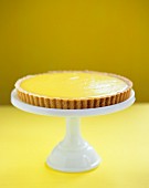 A Whole Lemon Tart on a Glass Pedestal Dish; Window in Background