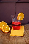 A plastic cup of Campari with a slice of orange
