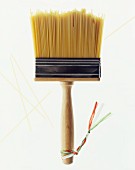 A paintbrush with bristles made of spaghetti and little ribbons in the Italian colours