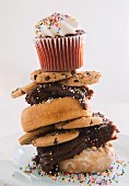 A stack of assorted biscuits, doughnuts and cake