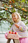 Girl standing on ladder eating freshly picked apple
