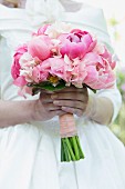 Bride holding bridal bouquet of pink peonies