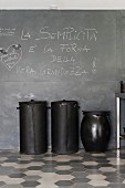 Black recycling bins made from upcycled car tyres against blackboard wall and on honeycomb tiles