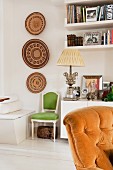 White sideboard decorated with framed photographs and elegant, antique table lamp next to African wall decorations