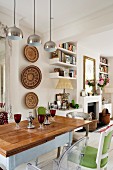 Country-house-style dining table and African wall decorations in open-plan interior