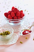 A spoon of raspberry and rose jam, chopped pistachios and fresh raspberries