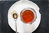 A jar of honey and a spoon on a plate