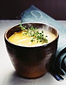 A bowl of steaming cream of vegetable soup with thyme