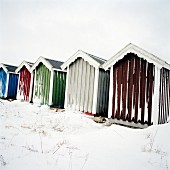 Snowy wooden beach huts painted different colours