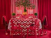 Dining table surrounded by red decor, Plants and candle on it