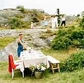 Frau deckt Tisch im Freien fürs Mittsommerfest (Schweden)