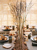 Gedeckter Tisch dekoriert mit Sand, Muscheln, Steinen & Gräsern