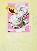 A coffee cup and pot, sugar cubes and raspberries