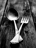 Rustic silver spoon and fork on a dark wooden table.