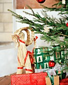 Pakete in Geschenkpapier und Tierfigur aus Stroh unter Weihnachtsbaum